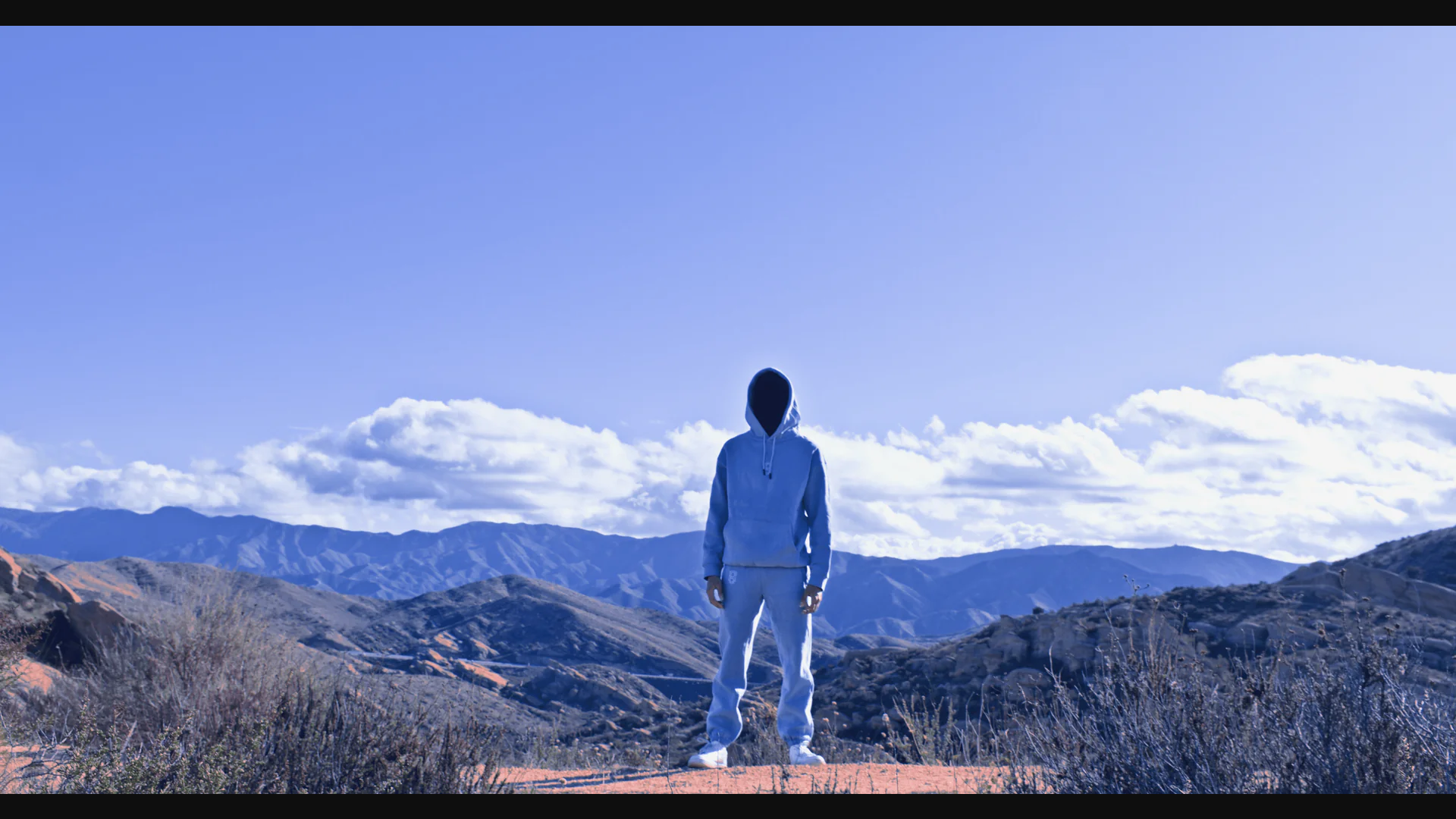 man standing on a hill in a hoodie